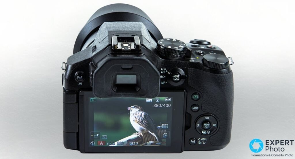 Panasonic Lumix FZ300 posé sur table en bois, zoom 25-600 mm déployé, pare-soleil visible sur l'avant