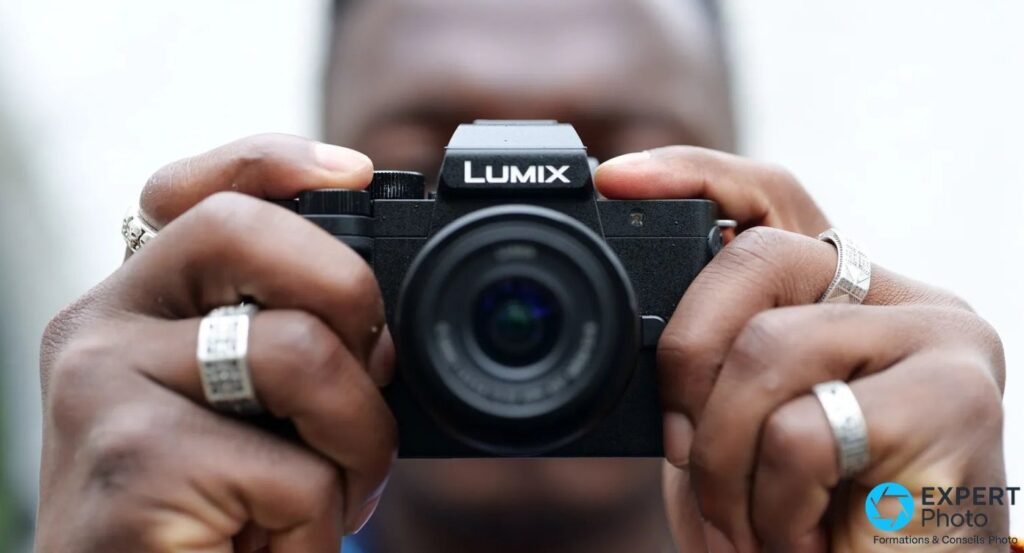 Panasonic Lumix G100 vu de dos sur trépied, viseur, molette de mode et volet USB Micro-B ouvert avec câble connecté