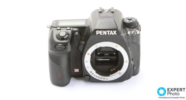 Pentax K-7 vu de face, boîtier nu, monture K-mount visible avec miroir, logo SR rouge de la stabilisation capteur.