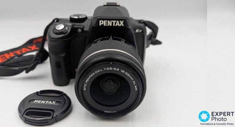 Reflex Pentax K-r noir avec objectif SMC Pentax-DAL 18-55mm f/3.5-5.6 monté, bouchon et sangle visibles