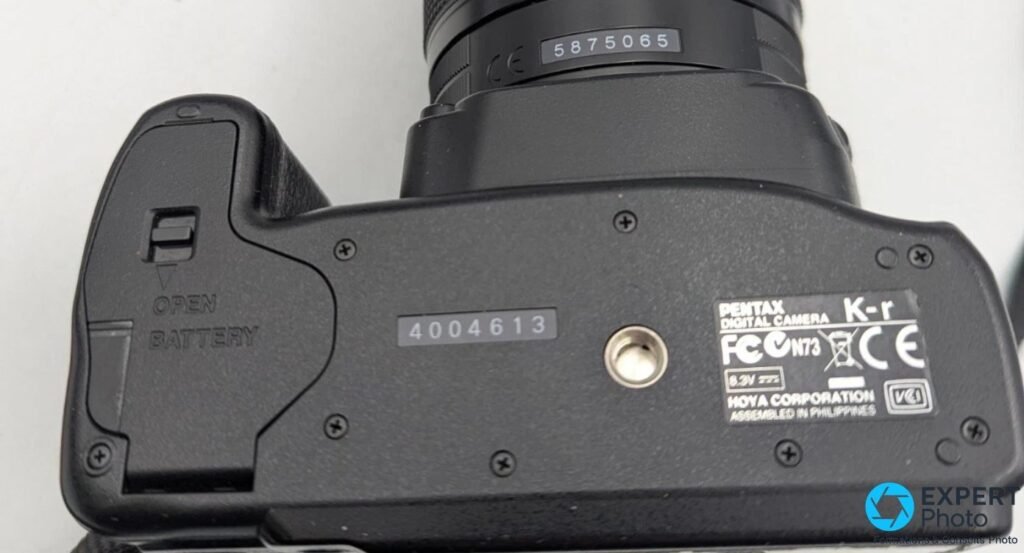 Dessous du Pentax K-r noir avec trappe batterie OPEN, numéro de série 4004613 et étiquette HOYA CORPORATION