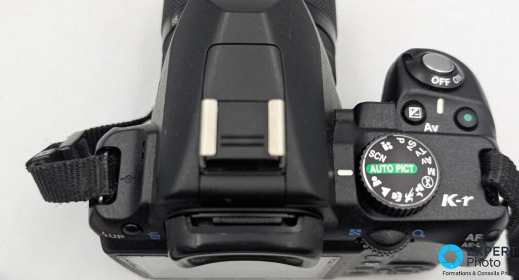 Dessus du Pentax K-r avec molette des modes en position AUTO PICT, griffe flash, déclencheur et bouton Av