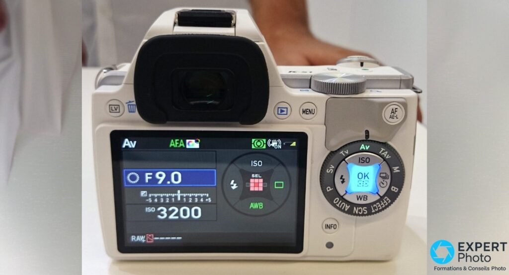 Dos du Pentax K-S1 blanc, écran LCD affichant F9.0 et ISO 3200, molette modes P Sv Tv Av TAv M B et bouton AF/AE-L. 