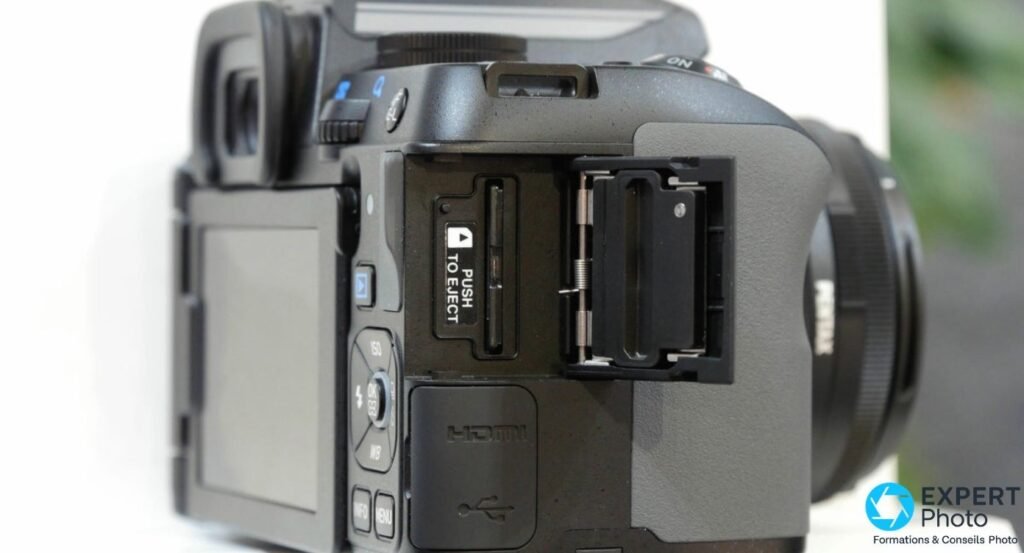 Base du Pentax K-S2 avec pas de vis trépied 1/4 pouce et trappe carte mémoire SD ouverte, carte insérée