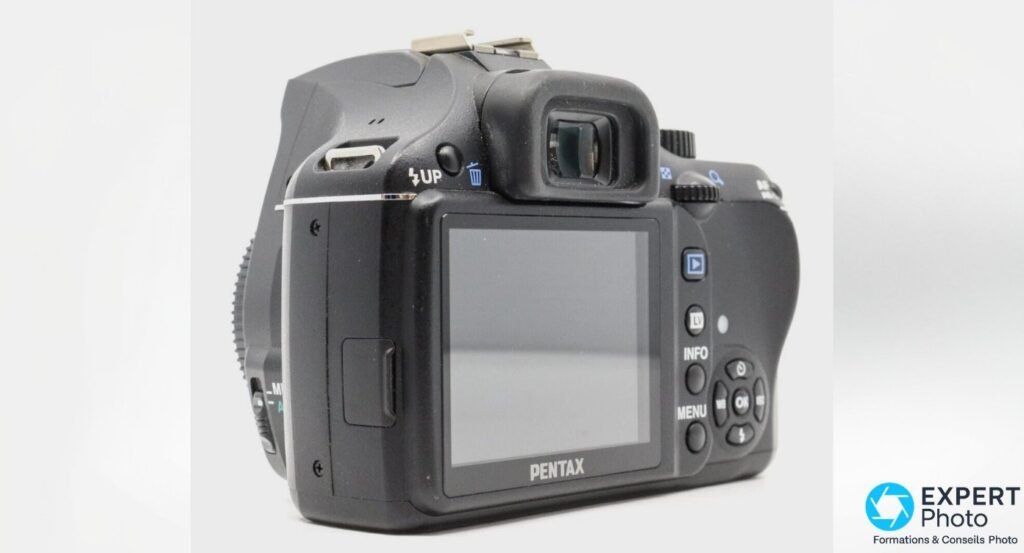 Pentax K-x vu de dos, écran LCD 2,7 pouces, œilleton du viseur, boutons MENU, INFO, OK et libération flash UP.