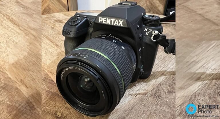 Pentax K-5 II avec objectif SMC Pentax-DA 18-55 mm f/3,5-5,6 monté, vue trois quarts avant sur parquet bois clair.