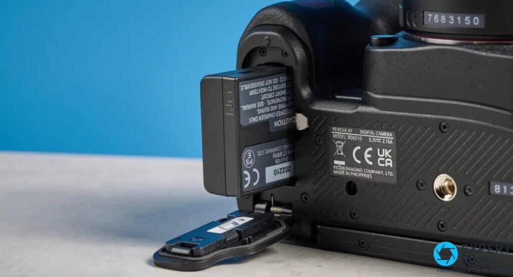 Pentax KF dessous avec trappe ouverte et batterie D-LI109, marquage Ricoh Imaging et Made in Philippines visibles 