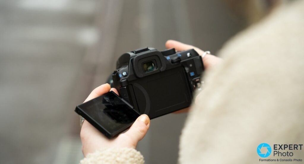 Pentax KF tenu par un utilisateur en extérieur, écran articulé déployé latéralement, vue arrière sur épaule
