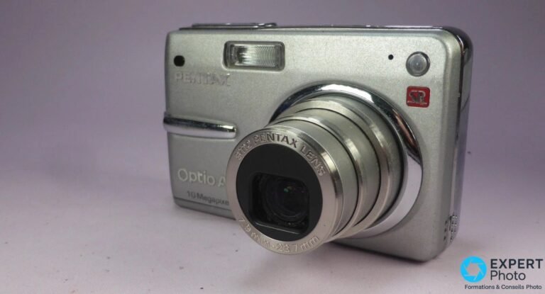 Pentax Optio A20 silver en vue 3/4 avant, objectif SMC Pentax 7,9-23,7 mm déployé, logo Pentax et badge rouge SR.