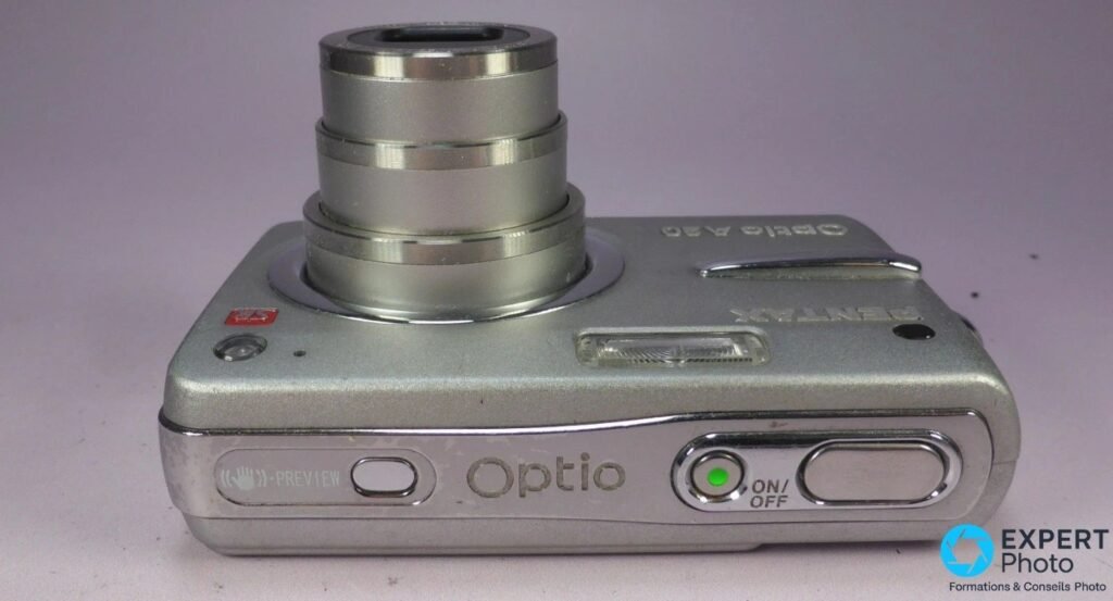  Pentax Optio A20 silver vu de dessus, objectif déployé, bouton PREVIEW avec icône stabilisation et inscription Optio.