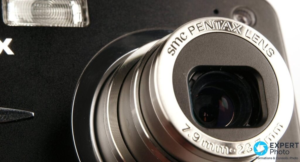 Gros plan objectif Pentax Optio A40, gravure smc PENTAX LENS 7.9mm - 23.7mm lisible, flash intégré visible à gauche. 