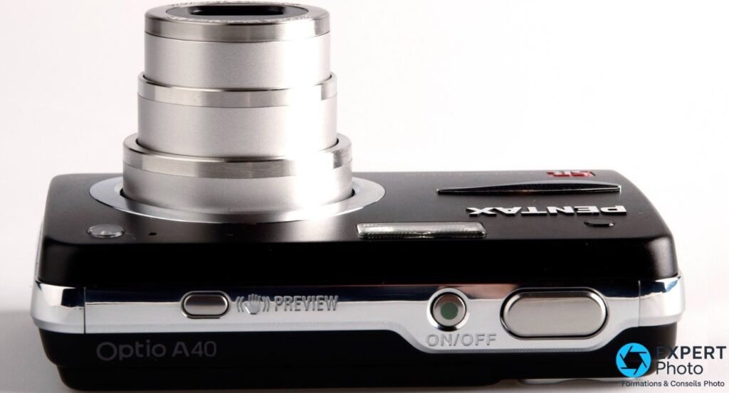 Pentax Optio A40 vu de dessus, marquage Optio A40 gravé, zoom déployé, boutons ON/OFF et PREVIEW, déclencheur.