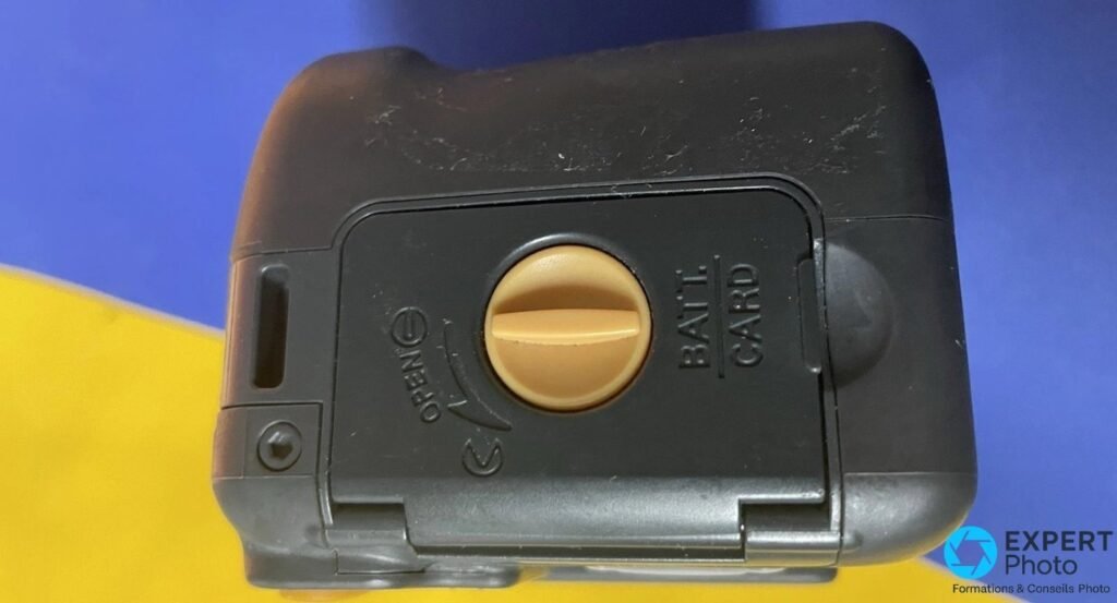 Trappe batterie/carte fermée du Ricoh Caplio 500SE avec verrou rotatif orange et marquage BATT./CARD.