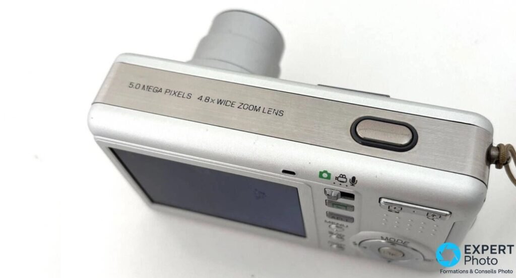 Ricoh Caplio R2 argenté en plongée 3/4 arrière, gravure 5.0 mégapixels 4,8x wide zoom et écran LCD 2,5 pouces visibles.