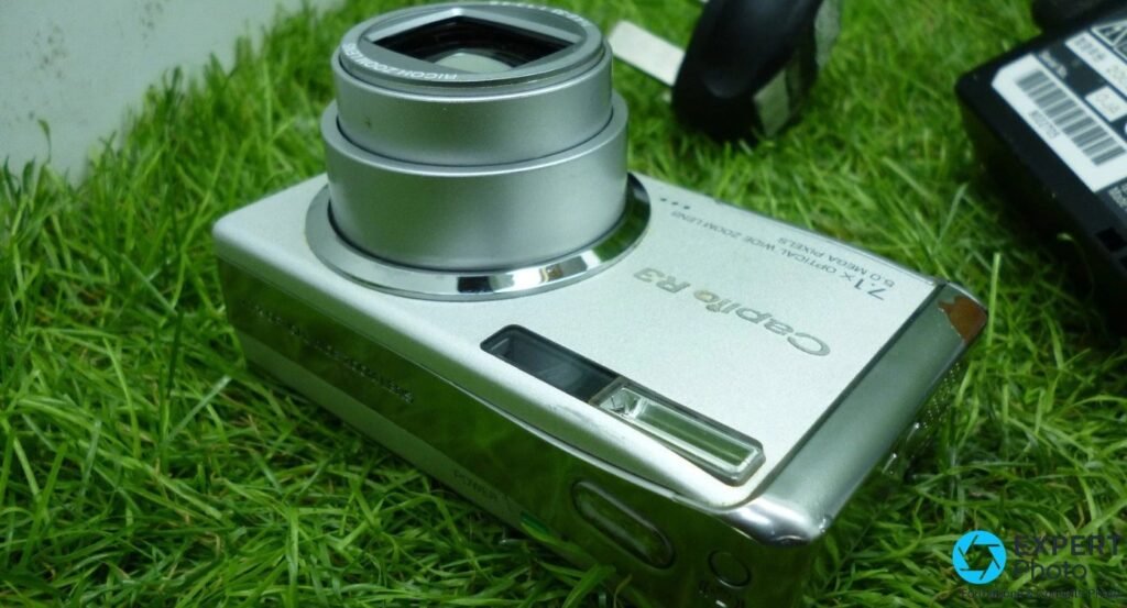 Vue de dessus du Ricoh Caplio R3, objectif Ricoh Zoom Lens déployé, viseur optique et déclencheur visibles. 