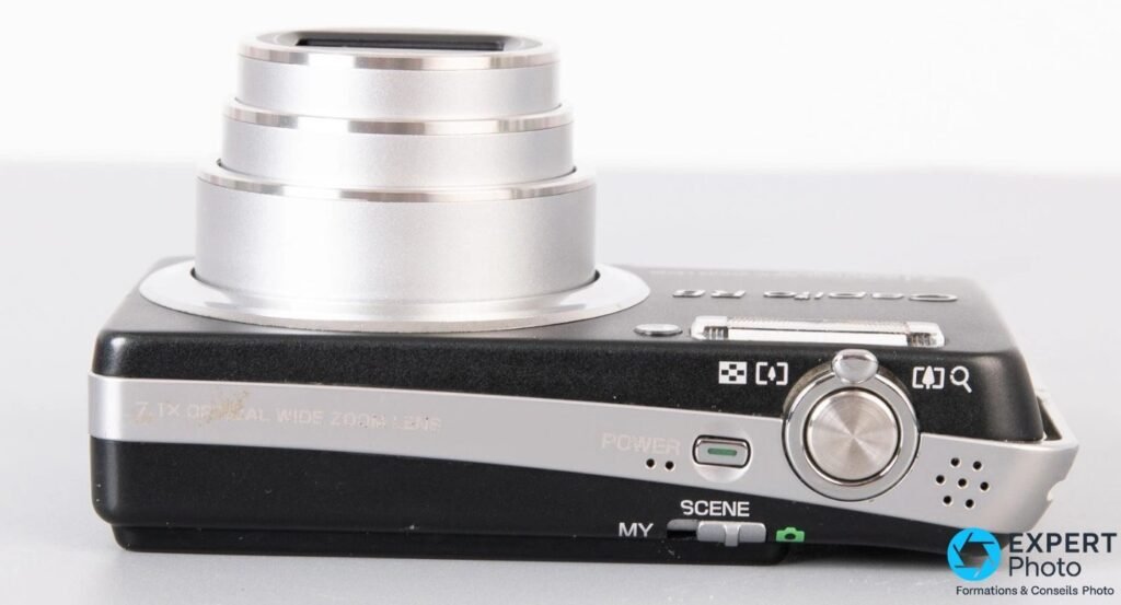 Ricoh Caplio R6 vu de dessus avec déclencheur, bouton Power, sélecteur MY/SCENE et zoom 7,1x déployé. 