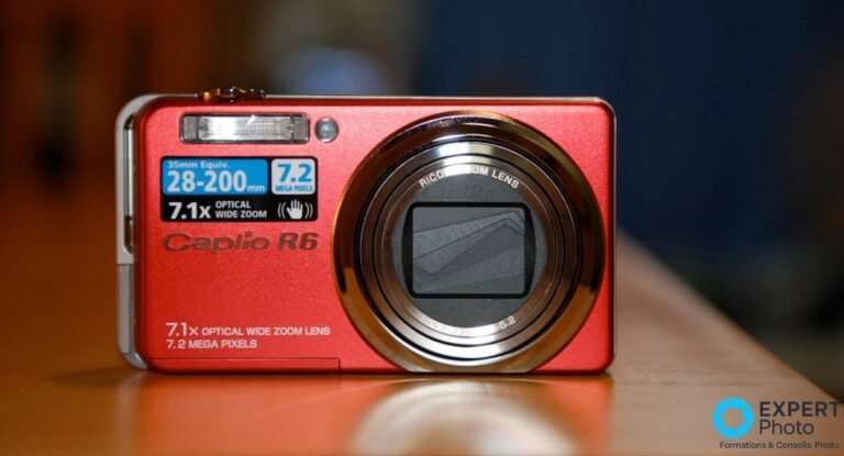 Ricoh Caplio R6 en finition rouge vu de face, objectif zoom 7,1x rétracté avec cache fermé, stickers 28-200 mm.
