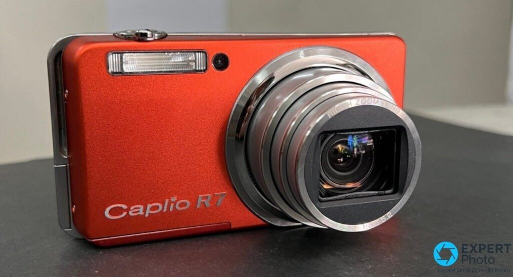 Ricoh Caplio R7 orange vu de face, objectif zoom déployé en position de prise de vue, marquage Ricoh Zoom Lens visible.