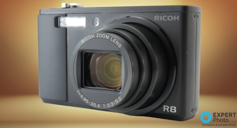 Compact Ricoh Caplio R8 noir vu de face en trois quarts, objectif zoom 28-200 mm déployé, logo R8 visible.