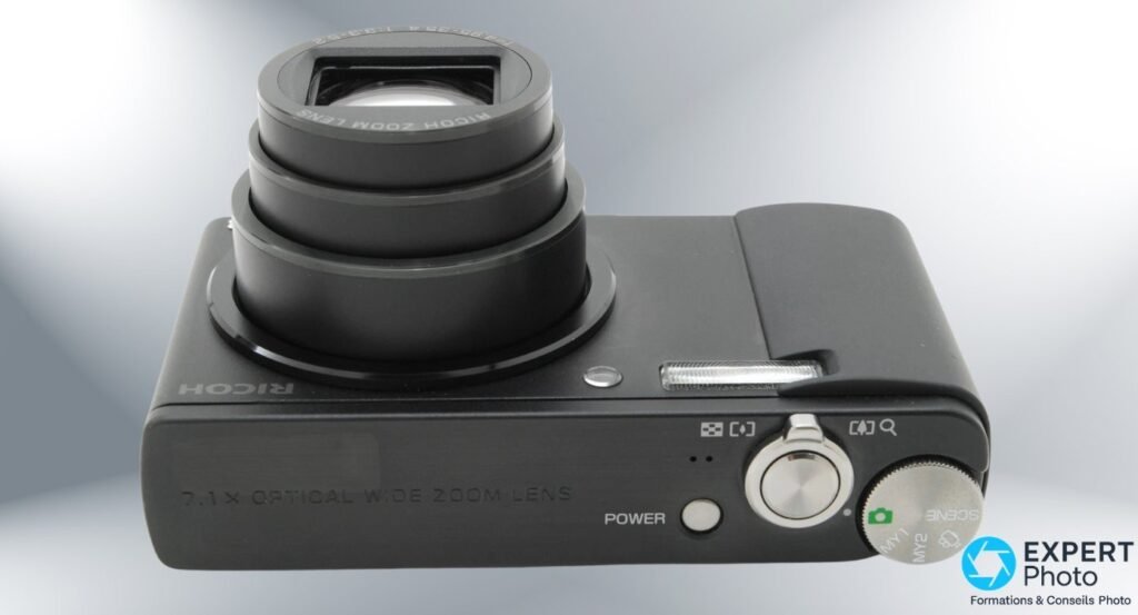 Ricoh Caplio R8 vu de dessus avec zoom optique 7,1× déployé, mention 7.1× OPTICAL WIDE ZOOM LENS sur le boîtier.