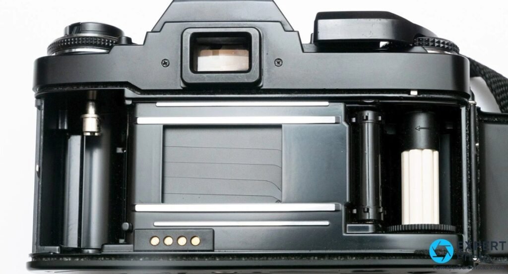 Dos ouvert du Ricoh XR-P : presseur, rails du film, bobine réceptrice à droite et contacts dos dateur en bas du couvercle