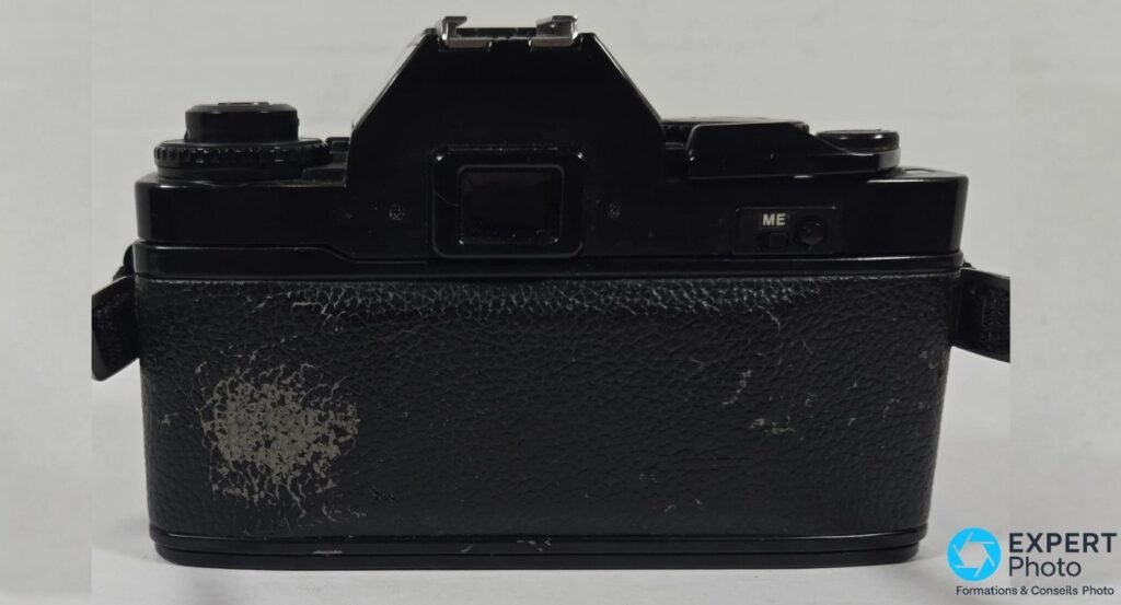 Dos du Ricoh XR-S, garniture en cuir noir avec usure visible côté gauche, viseur et bouton ME au-dessus.