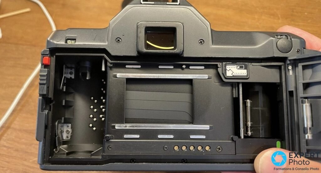 Ricoh XR-X dos ouvert, chambre film vide, rideau d'obturation, contacts DX et bobine réceptrice visibles