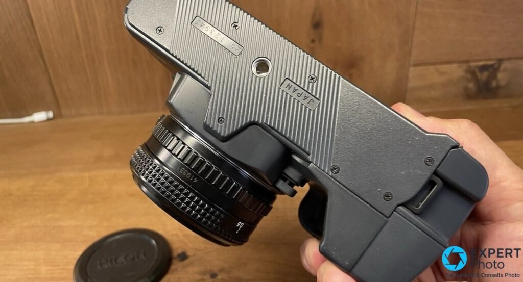 Dessous du Ricoh XR-X tenu en main, numéro de série gravé, marquage Japan et écrou de pied 1/4 visibles