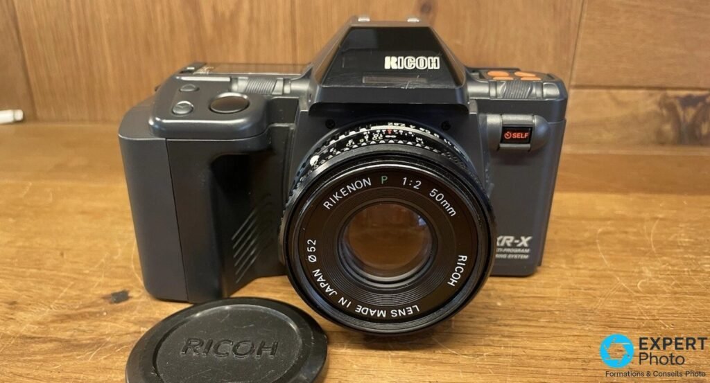 Ricoh XR-X de face, Rikenon P 50 mm f/2 monté et bouchon d'objectif RICOH posé devant le boîtier
