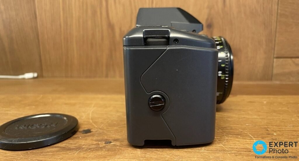 Profil du Ricoh XR-X, capot dos rabattu, griffe flash visible et amorce de l'objectif Rikenon à droite