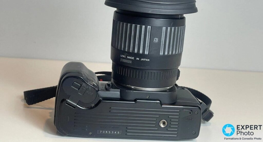 Sigma SA-300 vu de dessous, compartiment de la pile 2CR5 fermé, objectif Sigma marqué « LENS MADE IN JAPAN
