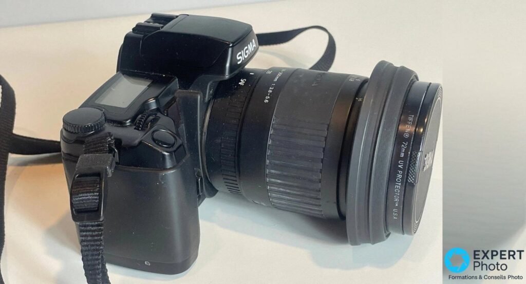 Sigma SA-300 vu de profil avec le pentaprisme estampillé SIGMA et le zoom 28-200 mm muni d'un filtre UV Tiffen 72 mm