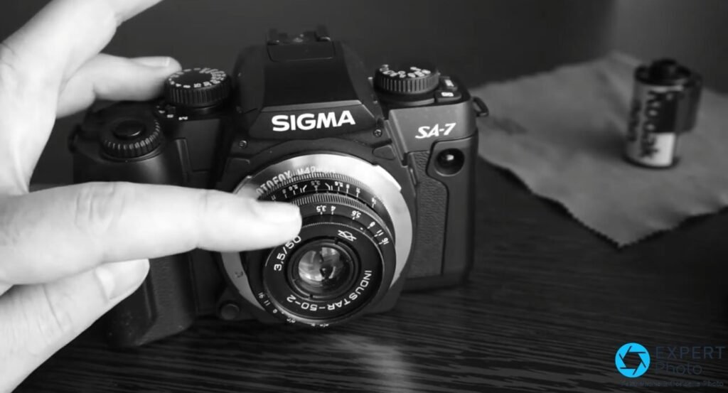 Mains réglant la bague d'ouverture d'un objectif manuel Industar-50-2 monté sur un Sigma SA-7 noir, photo noir et blanc.
