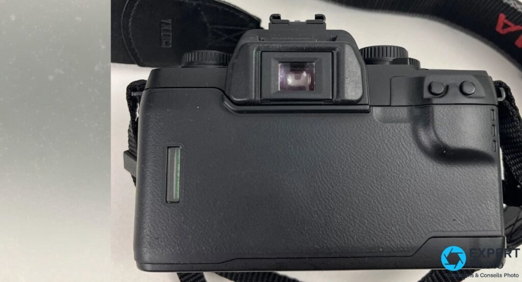 Vue arrière du reflex argentique Sigma SA-7 noir, œilleton du viseur, griffe flash et fenêtre rappel film visibles.