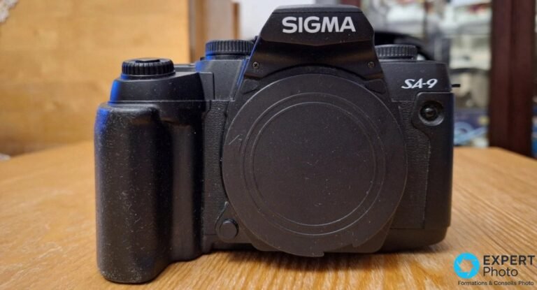 Sigma SA-9 vu de face, logo SIGMA sur le pentaprisme, marquage SA-9 et bouchon de baïonnette en place.