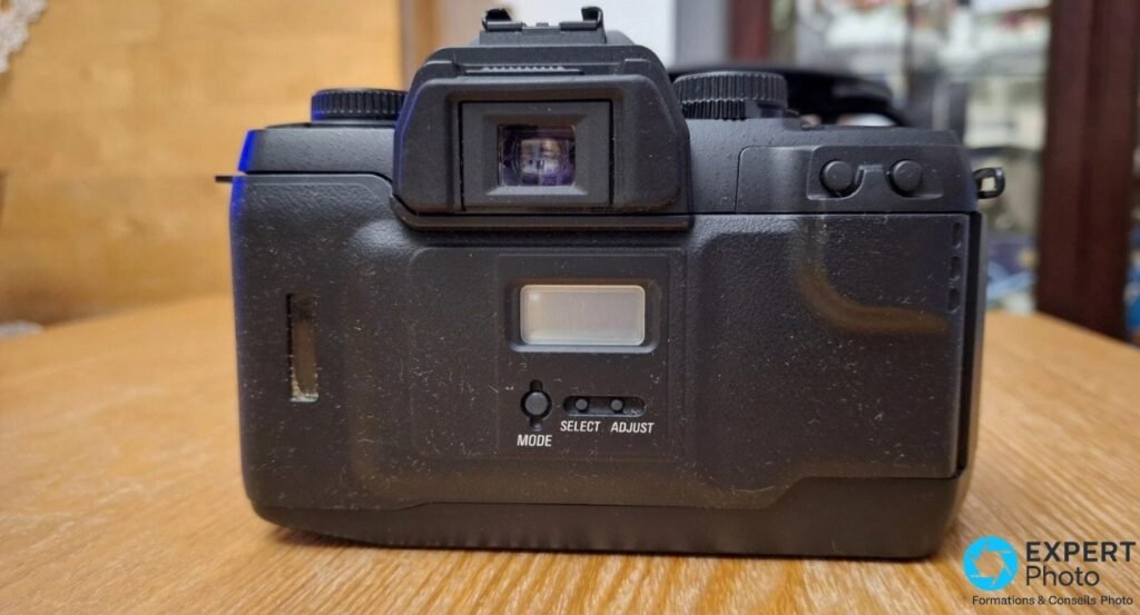 Vue arrière du Sigma SA-9 avec viseur central, écran LCD dorsal et boutons MODE, SELECT et ADJUST.