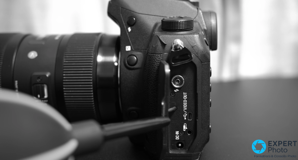 Panneau latéral du Sigma SD1 Merrill avec prises DC-IN, USB et Video-OUT — connectique datée sans HDMI ni Wi-Fi