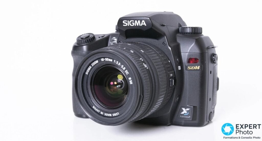 Sigma SD14 noir avec optique Sigma Zoom 18-50mm 3.5-5.6 DC montée, vue trois quarts avant, fond studio blanc.