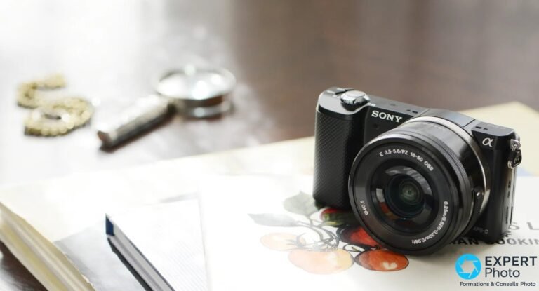 Sony A5000 noir équipé du zoom 16-50 PZ OSS, posé sur un livre ouvert, casse-noix flou en arrière-plan.