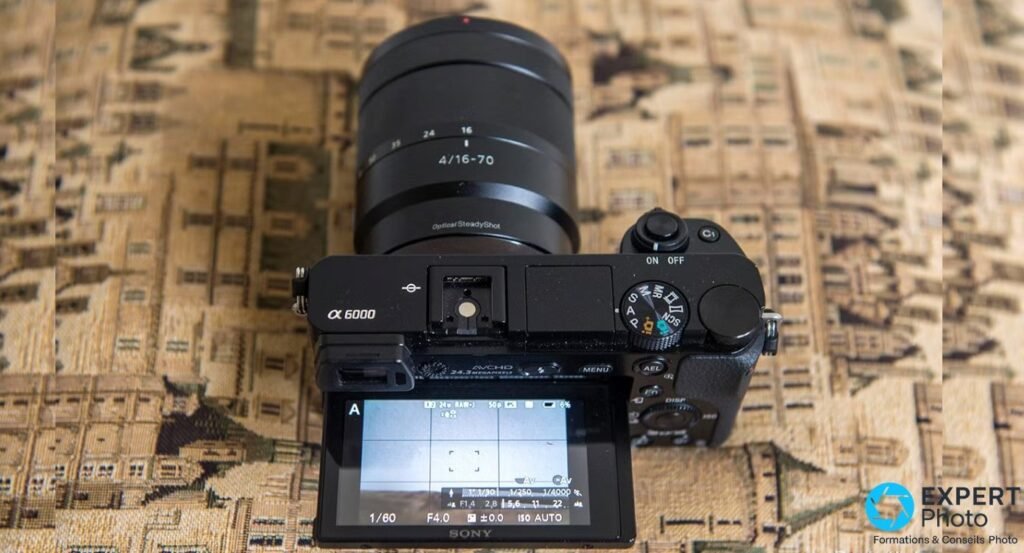 Sony A6000 vu de dessus, écran allumé affichant l'interface, objectif Zeiss 16-70 monté. 