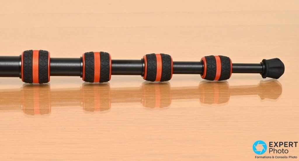 Jambe détachable du trépied 3 Legged Thing Corey 2.0, bagues de verrouillage noires et anneaux orange sur fond bois