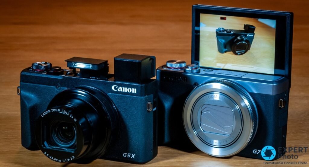 Canon G5 X Mark II avec flash relevé et G7 X Mark III avec écran retourné, posés côte à côte sur table en bois.