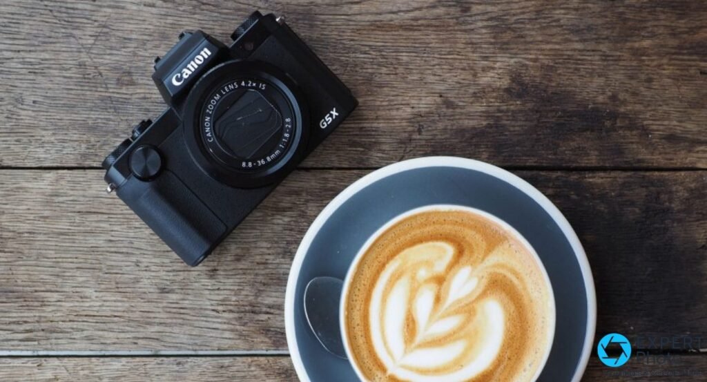 Canon PowerShot G5 X vu de dessus à plat sur planches en bois, tasse de cappuccino latte art
