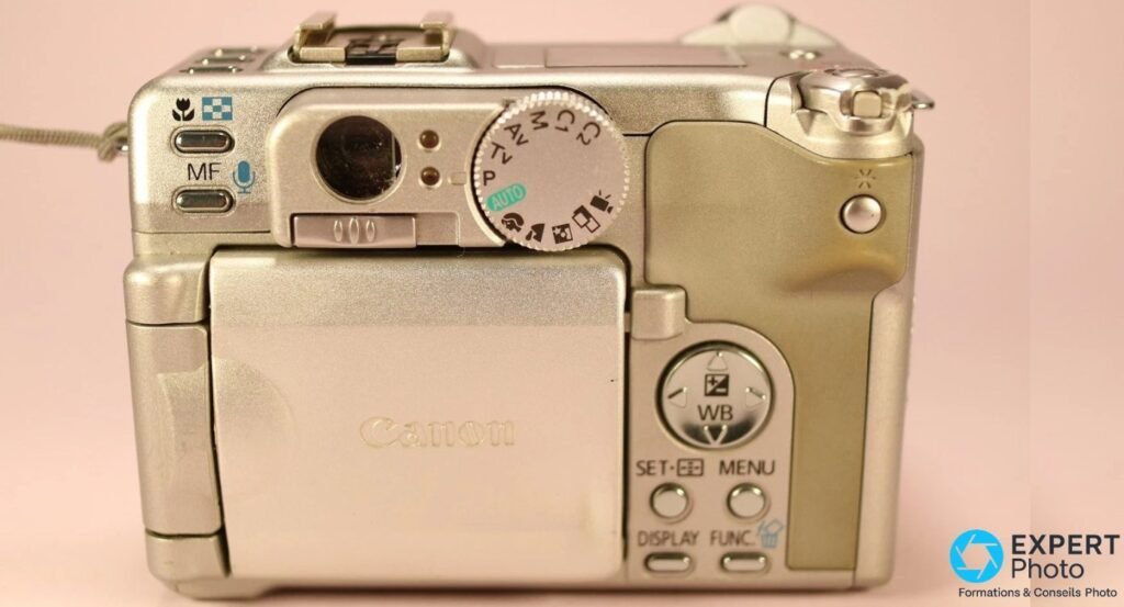 Canon PowerShot G6 vu de dos, écran orientable replié face Canon, molette PASM et boutons SET MENU DISPLAY visibles.