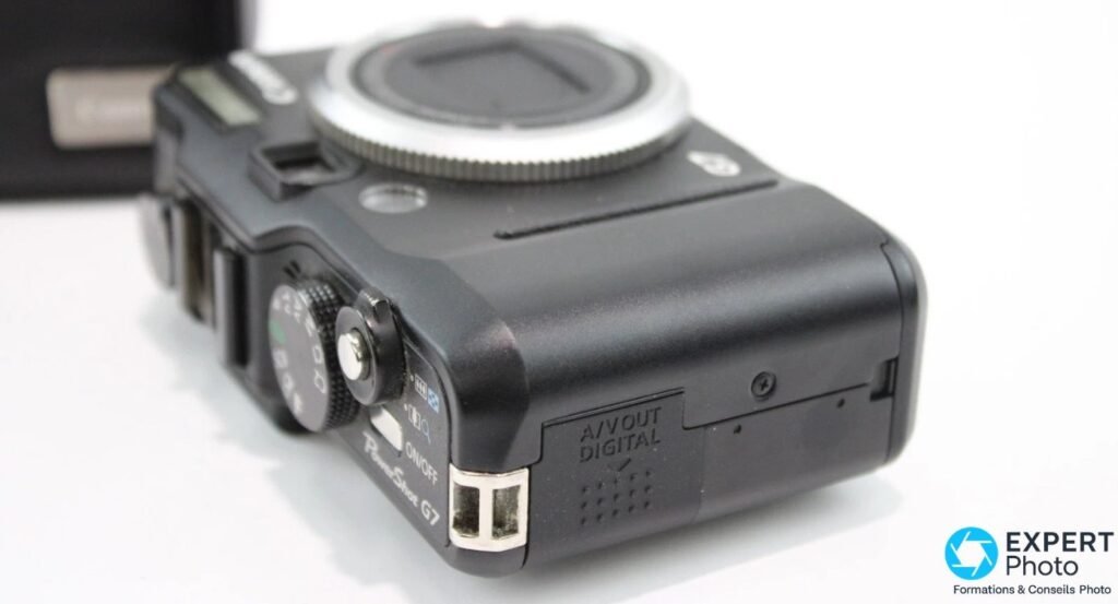  Canon PowerShot G7 côté droit, cache plastique du port A/V OUT DIGITAL ouvert, ON/OFF et molette ISO visibles.