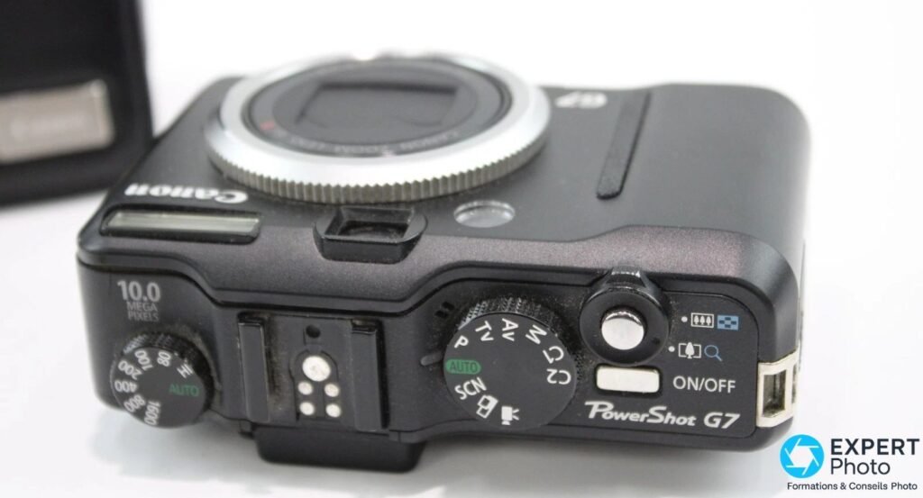 Canon PowerShot G7 vu de dessus, molette ISO 80 à 1600, sabot flash, molette de mode P/Tv/Av/M, marquage 10 Mpx. 
