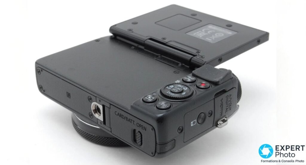 Canon PowerShot G7X vu de trois-quarts arrière par-dessous, écran articulé déployé, dessous du boîtier visible