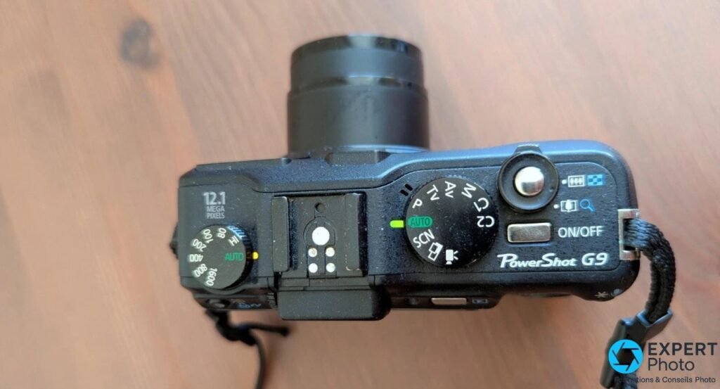 Canon PowerShot G9 vu de dessus, molette ISO graduée 80-1600, griffe flash, molette de modes et inscription PowerShot G9.