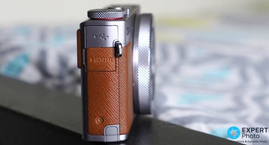 Profil droit du Canon PowerShot G9 X Mark II avec trappe USB ouverte et port HDMI marqué sous le grip cuir marron. 