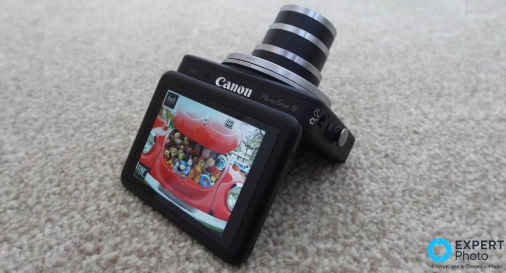 Canon PowerShot N en 3/4 arrière, écran tactile incliné affichant une photo, logo Canon et mention PowerShot N visibles 